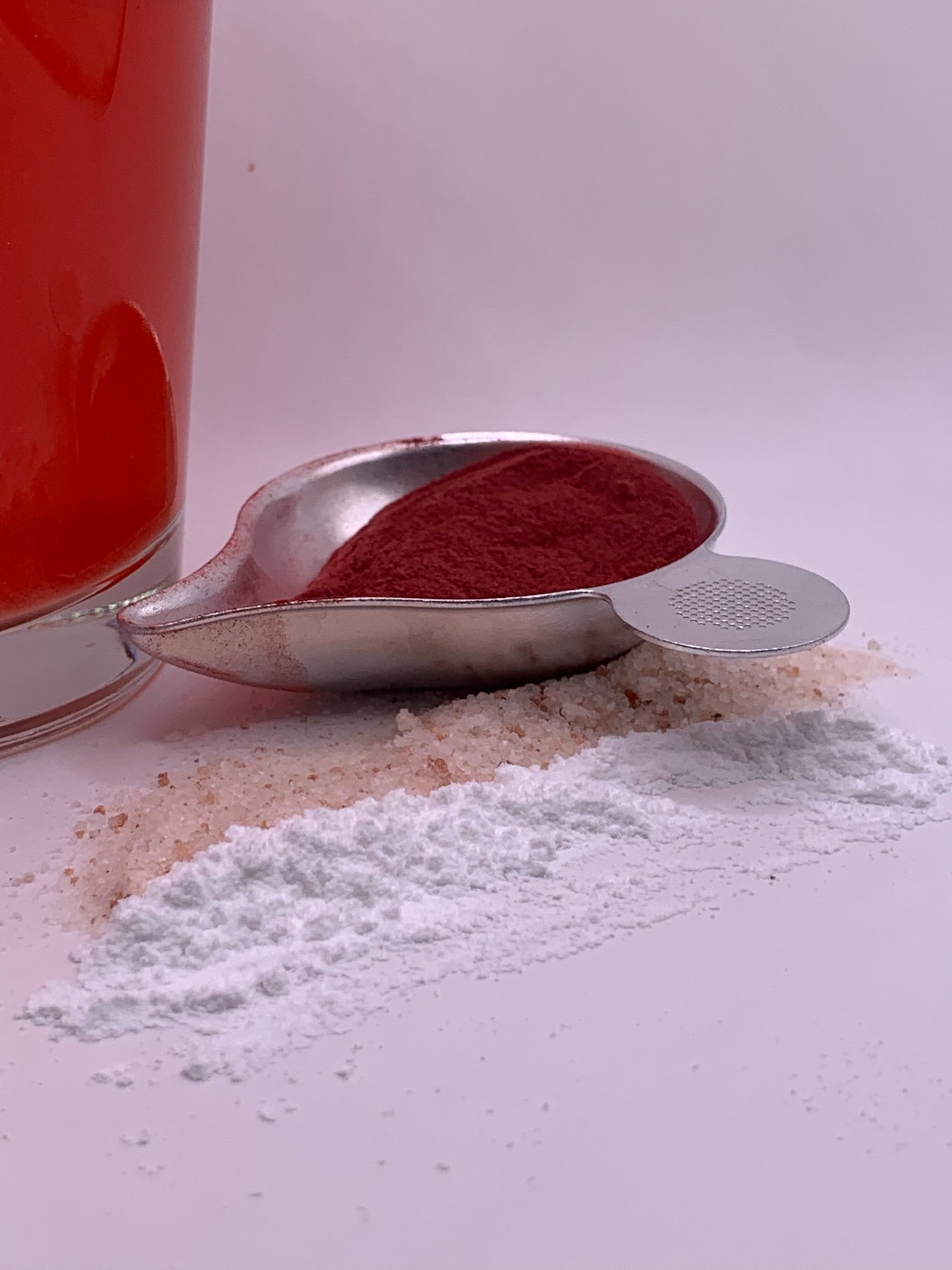 Scoop of workweek edge supplement powder next to white powder ingredients and a glass of red drink